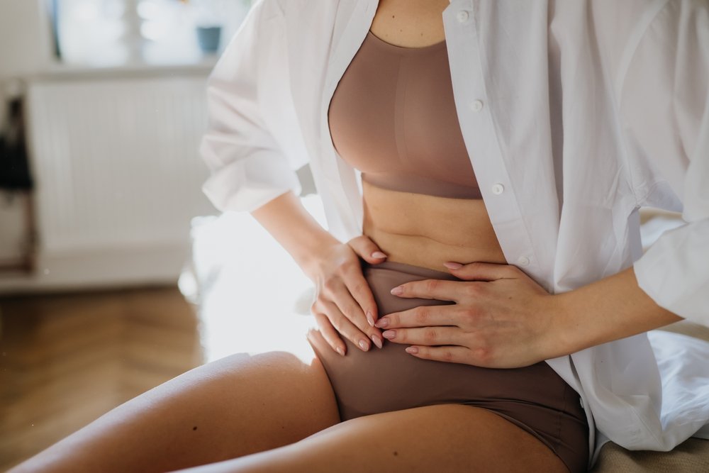 A woman holding her abdomen, suffering from PMS cramping.