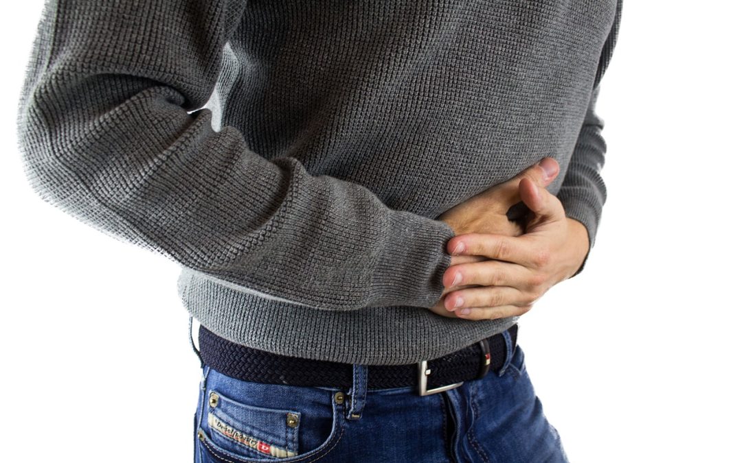 A man holding his stomach because of bloating.